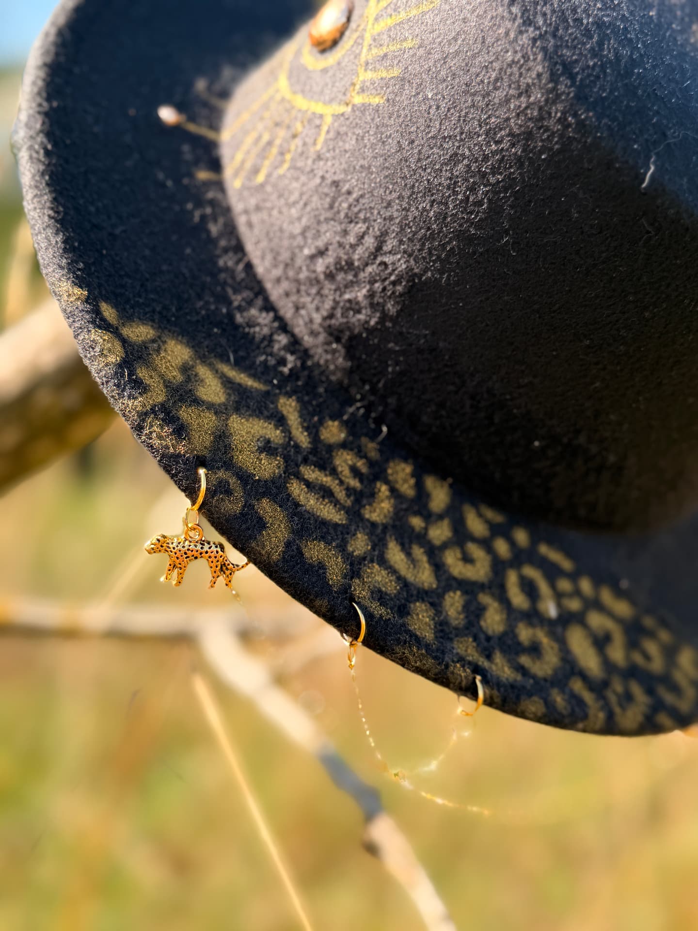 The Oracle detail with gold leopard and chain ornaments beneath the brim