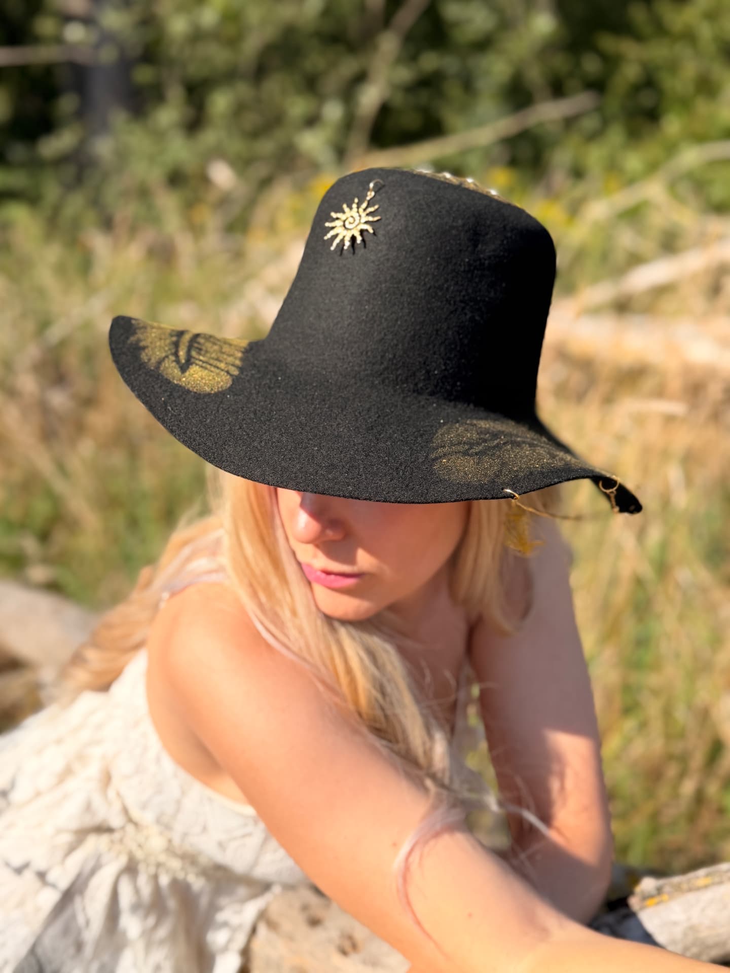 Aurea, a black felt hat with golden feathers and a golden sunburst ornament